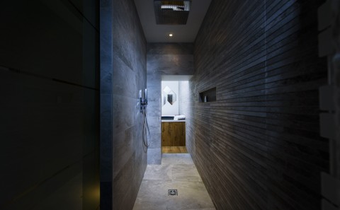 Une salle de bain aux murs en pierre, avec une douche au plafond, donne sur un spa